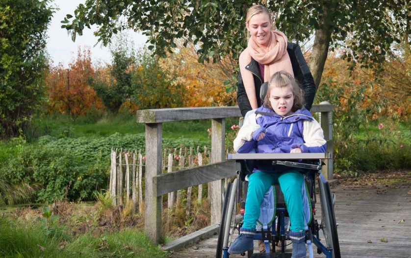 A disabled girl in a wheelchair relaxing outside together with a care assistant