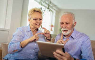Smiling deaf senior couple talking using sign language on the digital tablet's cam
