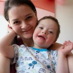 Selfie of cute small boy with Down syndrome with his mother