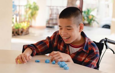 child in wheelchair molding clay