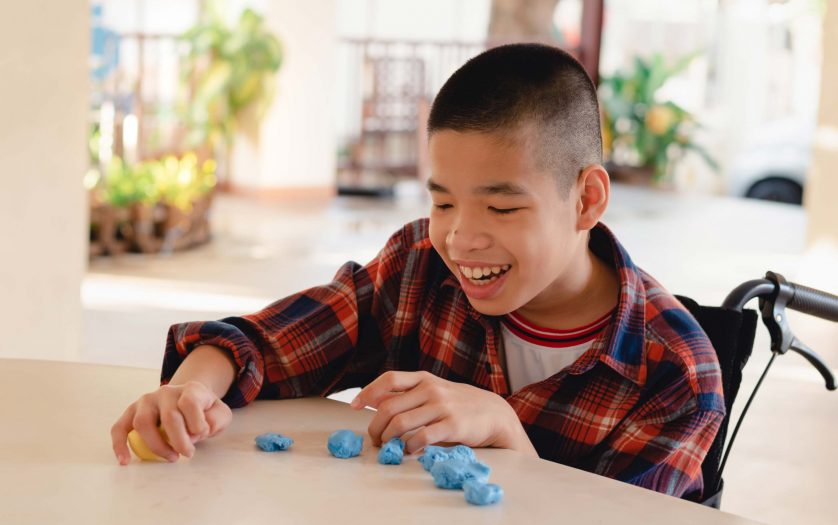 child in wheelchair molding clay