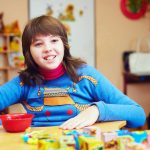Portrait of happy kid with disability develops fine motor skills at rehabilitation center