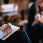 Researcher with unrecognizable patient, talking, taking notes
