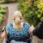 Disabled woman in wheelchair with assistant walking in garden