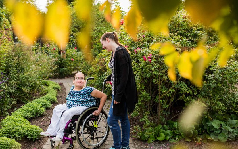 woman in wheelchair with assistant in garden