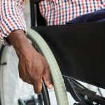 Close-up of African man sitting in wheelchair and holding the wheel
