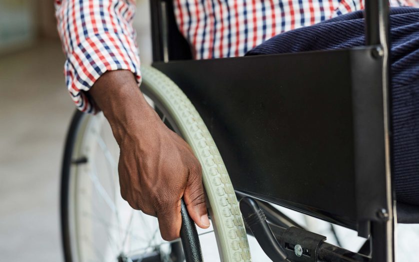 Close-up of African man sitting in wheelchair and holding the wheel