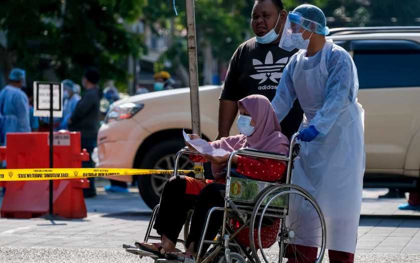 Medical personnel helps a woman in wheelchair to do the COVID-19 test to taking nasal and mouth swab at Kampung Baru.
