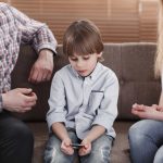 Close-up of boy with autism sitting between worried mother and father