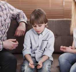 Close-up of boy with autism sitting between worried mother and father