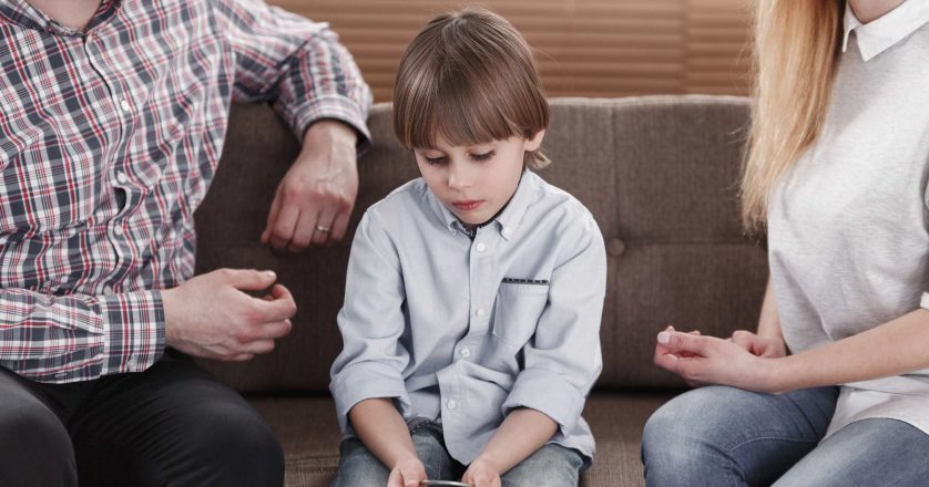 Close-up of boy with autism sitting between worried mother and father