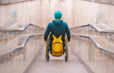 man in wheelchair going down the long ramp in the subway