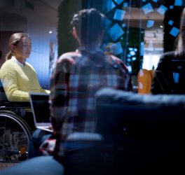 young woman in wheelchair with colleagues working in office