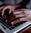 cropped shot of african-american man typing on laptop