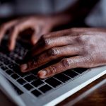 cropped shot of african-american man typing on laptop