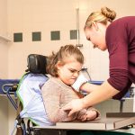 girl in a wheelchair being cared for by a carer in a specially adapted bathroom