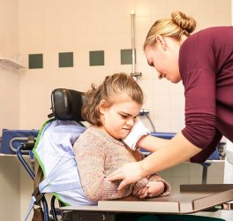 girl in a wheelchair being cared for by a carer in a specially adapted bathroom