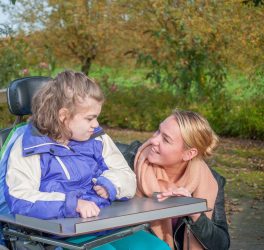 A disabled child in a wheelchair being cared for by a care worker