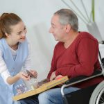 Photo of happy elderly men with disability and helpful nurse