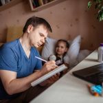 father looking at laptop screen and consulting with a doctor online at home