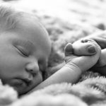 New born baby sleeping while holding mothers finger