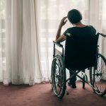 woman in wheelchair looking out the window and thinking