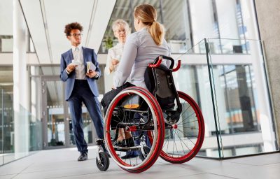 woman in wheelchair talking with colleageues during a break