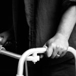 Close-up of woman holding for walker and trying to walk over black background