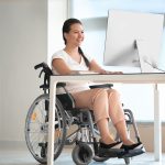 Asian woman in wheelchair working with computer in office