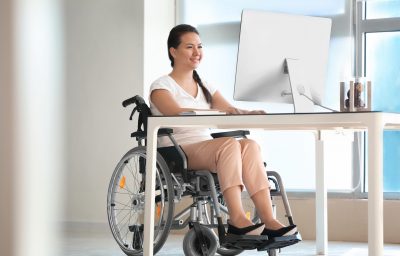 Asian woman in wheelchair working with computer in office