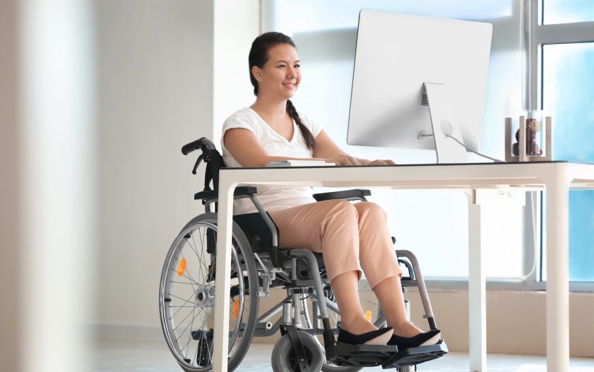 Asian woman in wheelchair working with computer in office