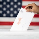 Concept of Mail in vote at US election - hands dropping mail inside the ballot box with us flag as background