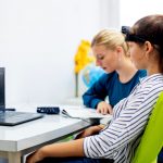 Young teenage girl and child therapist during an assessment session with computer