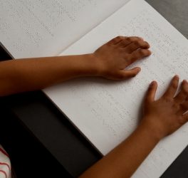 schoolboy hands reading a braille book in classroom