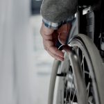 Close-up view of senior man hand on wheel of wheelchair