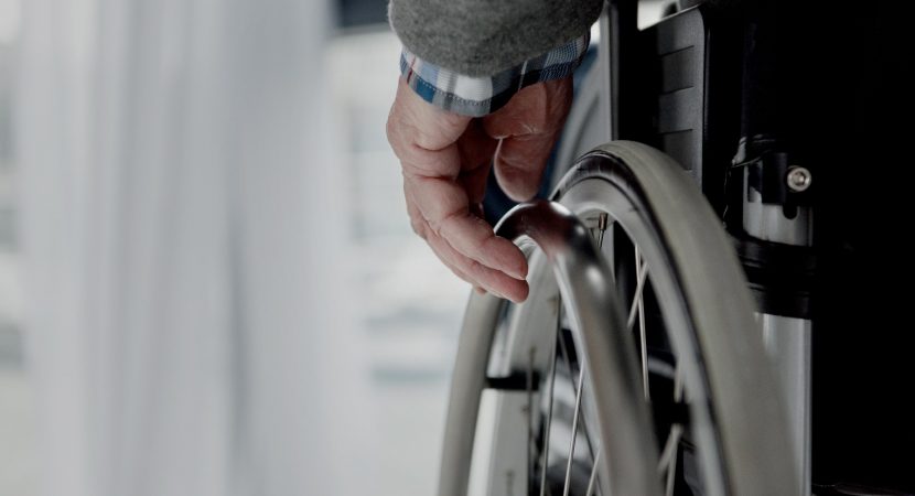 Close-up view of senior man hand on wheel of wheelchair