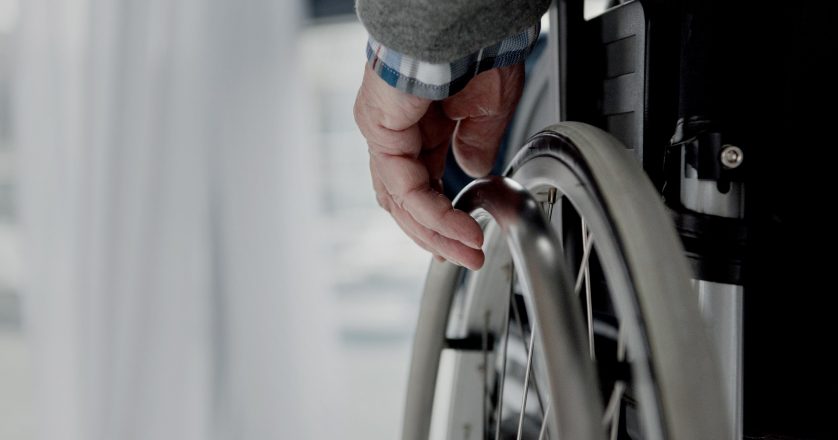 Close-up view of senior man hand on wheel of wheelchair