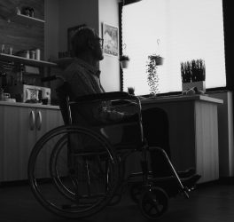 Silhouette of man in wheelchair feeling lonely looking on the window