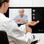 Doctor and senior women taking the pulse together, telemedicine and videotelephony for medical health care