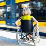 Woman sitting on wheelchair on a train platform ready to get in to the train