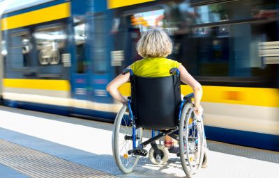 Woman sitting on wheelchair on a train platform ready to get in to the train