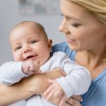 portrait of young mother holding infant in hands