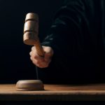 Hand banging gavel on dark background, the judge makes a verdict