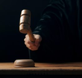 Hand banging gavel on dark background, the judge makes a verdict
