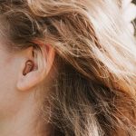 small intra channel hearing aid in the ear of a woman