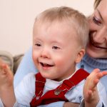 A closeup portrait of a mother holding her smiling and happy young son with Down Syndrome.