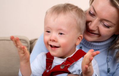 A closeup portrait of a mother holding her smiling and happy young son with Down Syndrome.