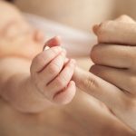 Newborn baby holding mother's hand