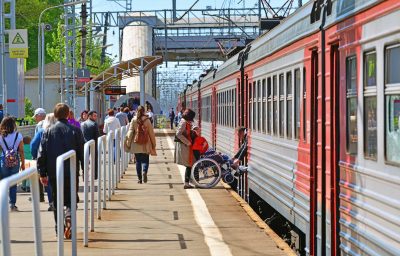 people helping a man in a wheelchair enters a train.