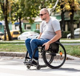 man in wheelchair crossing street road.